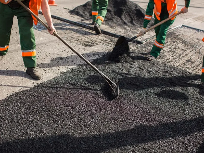 Builder during Asphalting road works level raw material before the operation of the machine